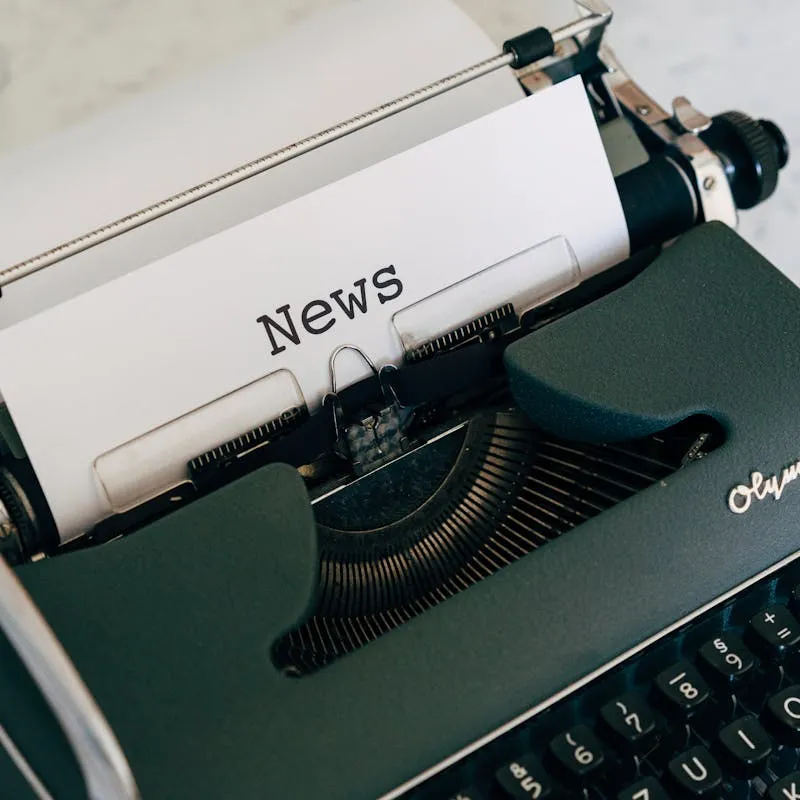 Close-up of an antique typewriter with 'News' on paper.
