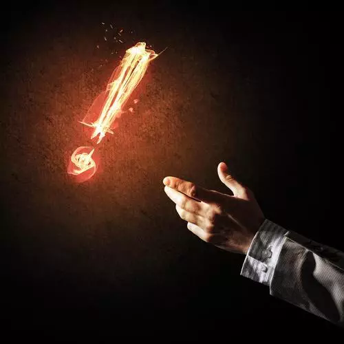 Businessman hand and fire glowing exclamation mark